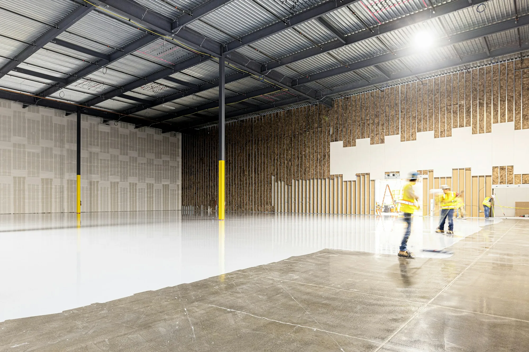 Workers cleaning a large, freshly finished warehouse floor